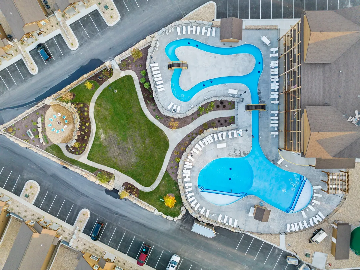 This image features two outdoor swimming pools surrounded by a beautifully landscaped garden, with lounge chairs and a comfortable seating area around a fire pit. The pools are inviting, and the setup is clearly designed for families to relax, swim, sunbathe, and enjoy quality time together outdoors.