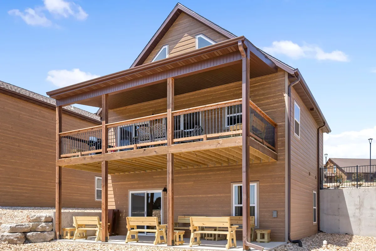 This exterior scene highlights a spacious two-story balcony adorned with wooden seating and large windows, offering ample space for outdoor dining, socializing, and enjoying scenic views together.