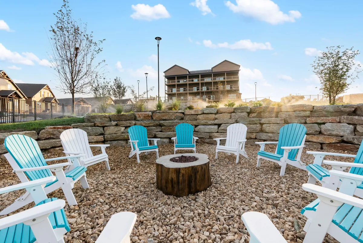 This exterior image features a cozy fire pit area surrounded by Adirondack chairs, set within landscaped grounds. The arrangement encourages group gatherings, storytelling, and bonding under the stars, embodying a sense of community and togetherness for all ages.
