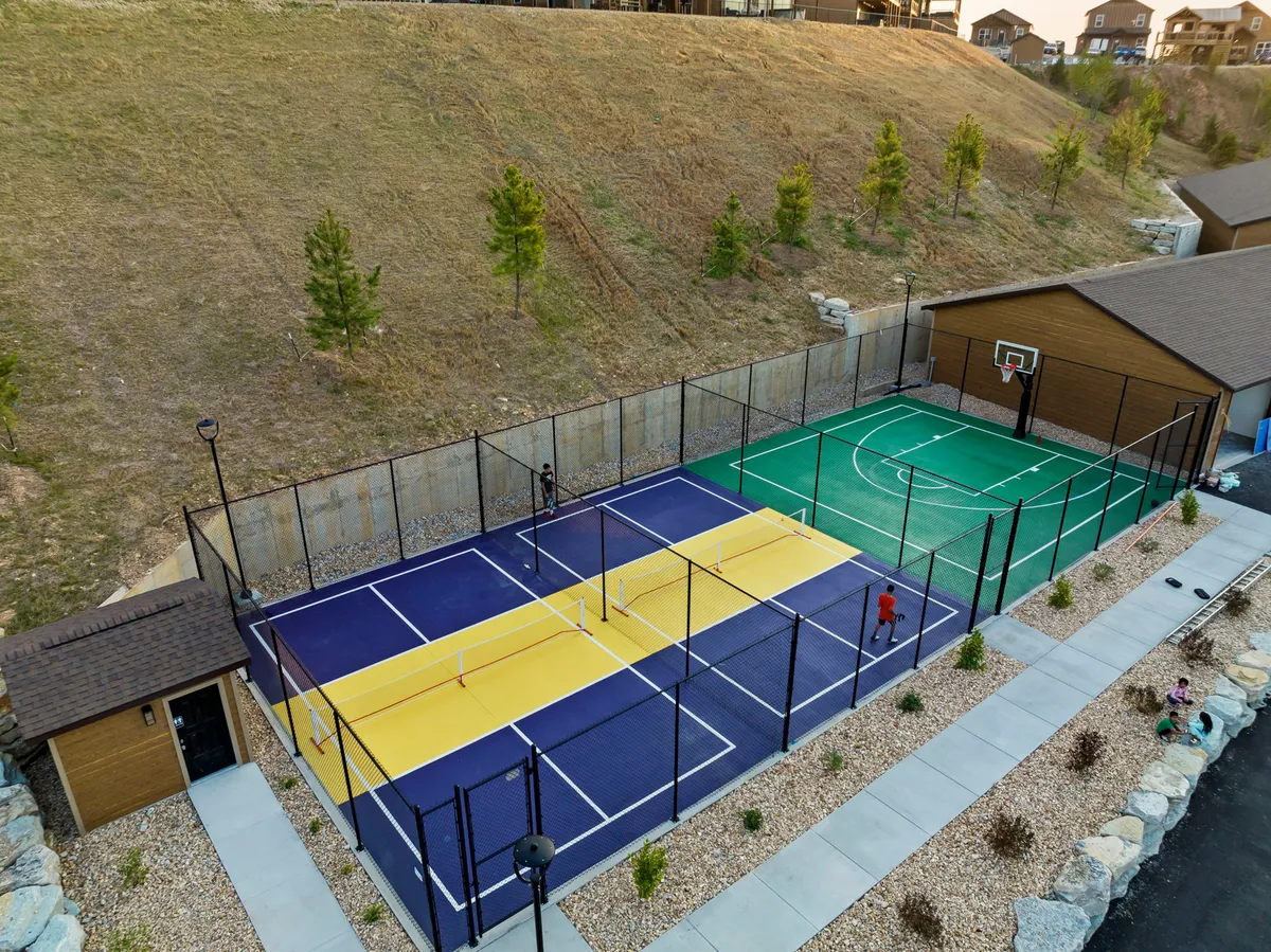 A dynamic exterior shot showcasing tennis and basketball courts set against a well-lit, landscaped backdrop. The courts are ready for friendly tournaments and active play, creating an atmosphere of excitement and camaraderie.